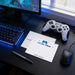 a gaming setup with a computer monitor, keyboard, and mouse, along with a white envelope and a black pen on a desk.