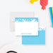 a white envelope with a blue water splash design, a white paper with a blue water splash design, and a red pineapple toy.