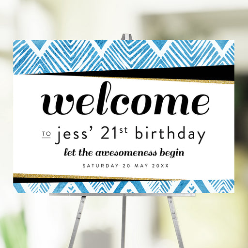 Blue geometric 21st birthday welcome sign displayed on an easel for a milestone birthday celebration.