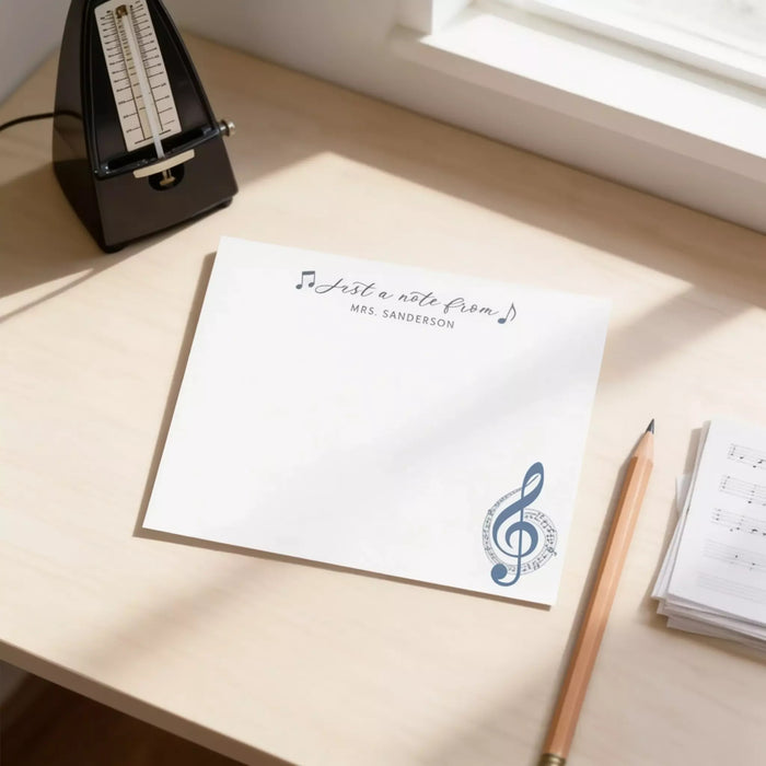 a desk with a blank white note card, a pencil, and a metronome.