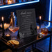 a drinks menu displayed on a table, surrounded by various drinks, candles, and a skull decoration.