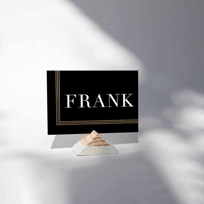 a black rectangular card with the word "FRANK" written on it, placed on a white surface.