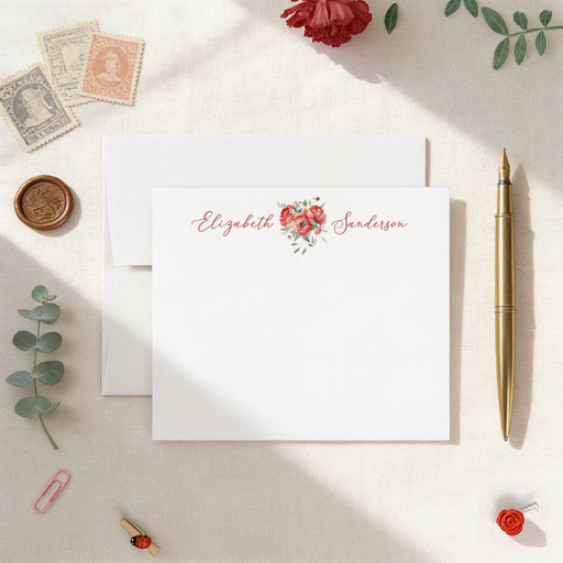 a white card with a floral design, surrounded by various stationery items such as a pen, a rose, and a stamp.