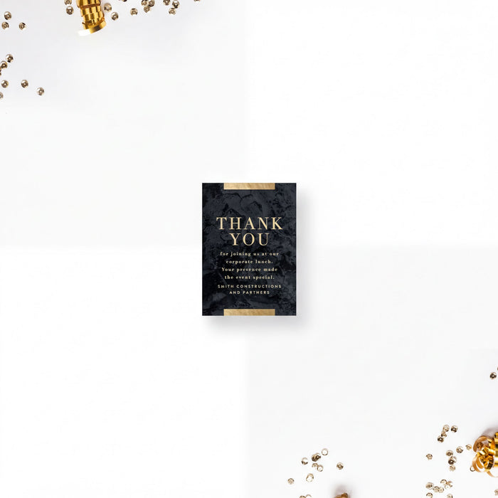 a black card with a gold text design, placed on a white background with scattered gold confetti.