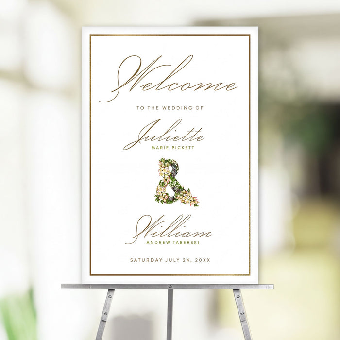 Elegant wedding welcome sign with gold border, floral ampersand, and personalized names, displayed on an easel for entrance decor.