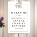 Elegant welcome sign with grapevine illustration for wine-themed charity banquet celebrations.