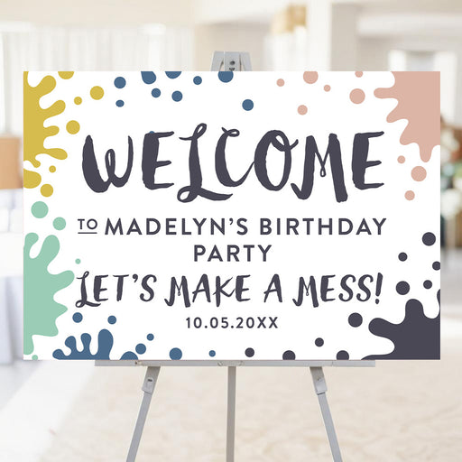 Art-themed birthday welcome sign with colorful paint-splatter design displayed on an easel for kids' party entrance.