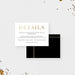 a white card with black text and gold lettering, placed on a white background with scattered gold confetti around it.