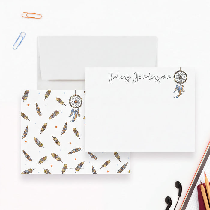 a white envelope with a dreamcatcher design, a blank card with a nameplate, and various office supplies such as a stapler, scissors, and a pencil.