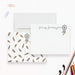 a white envelope with a dreamcatcher design, a blank card with a nameplate, and various office supplies such as a stapler, scissors, and a pencil.