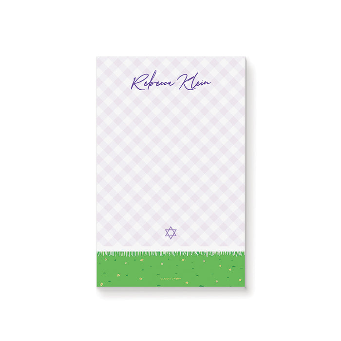 Personalized bat mitzvah notepad with a lavender picnic blanket, purple script name, and a green grass border with flowers
