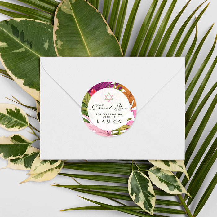 White envelope with a floral label on a background of green leaves