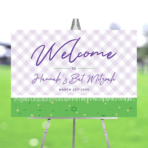 Bat Mitzvah welcome sign with purple check pattern and garden design displayed on an easel for event entrance decor