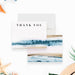 beach wedding thank you card with blue ocean wave artwork, sand-toned accents, couple names, and coastal design-front-back