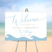 Beach wedding welcome sign featuring hand-drawn blue ocean waves and personalized couple names.