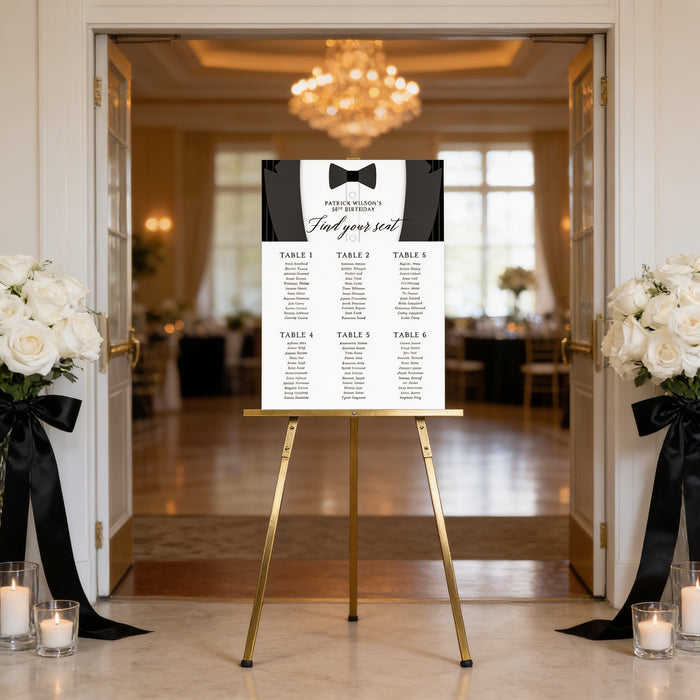 Personalized black and white black tie wedding seating chart sign displayed on a gold easel at an elegant reception entrance.