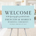 Modern blue wedding welcome sign with elegant typography displayed on easel for ceremony entrance.