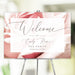 blush rose floral tea party welcome sign with elegant script lettering and personalized event details displayed on an easel
