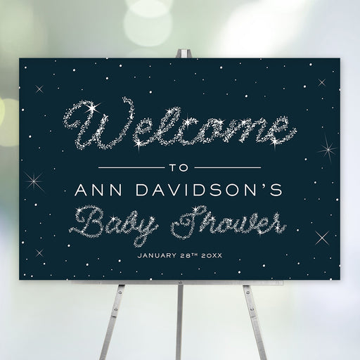 Celestial baby shower welcome sign with navy blue starry background and sparkling silver text, personalized with name and date, displayed on easel.