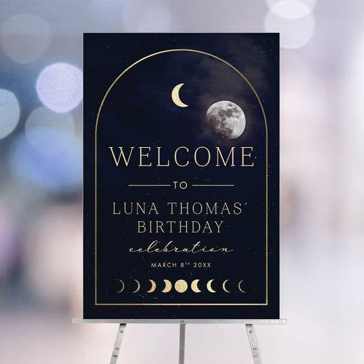 Celestial birthday welcome sign featuring moon phases, a gold arch, and a navy starry night sky, displayed on an easel.
