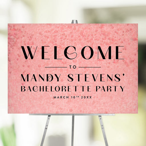 Pink bachelorette party welcome sign featuring a champagne bubble design, with a custom name and date on an easel.