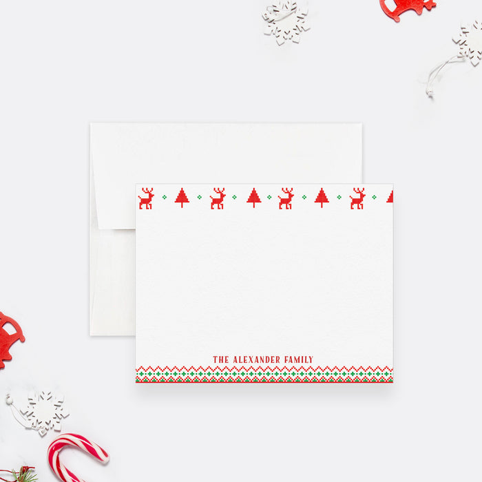 Personalized Christmas note card front with red reindeer, trees, green patterned borders and a family name, shown with a white envelope.