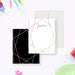 White personalized note card framed with multicolored gem outlines, beside a black back with matching geometric lines.