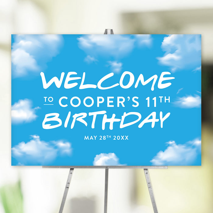 Personalized sky-themed birthday welcome sign with blue background and fluffy white clouds, custom name, age, and date, displayed on easel for party décor.