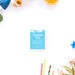 a blue "Thank You" card surrounded by various objects, including a blue seashell, an orange slice, and a straw wrapper.