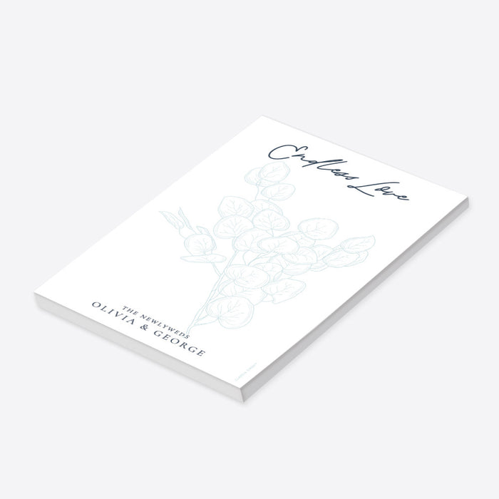 personalized botanical notepad with pale blue foliage design, elegant script lettering, and the newlyweds' name-side