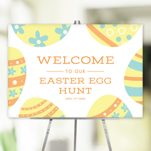Colorful Easter Egg Hunt welcome sign with pastel yellow, blue, and orange Easter egg illustrations, displayed on an easel for a spring party or community event.