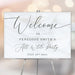 all white party welcome sign with elegant black script lettering, custom event details, and modern minimalist design displayed on an easel