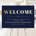 corporate anniversary welcome sign with navy background, gold-colored welcome lettering, and personalized business event details displayed on an easel