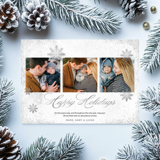 Elegant silver holiday photo card featuring three family photos, snowflake accents, and “Happy Holidays” script text on white background.