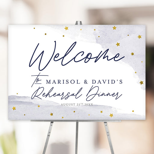 Custom watercolor rehearsal dinner welcome sign featuring gold stars and personalized names, displayed on an easel.