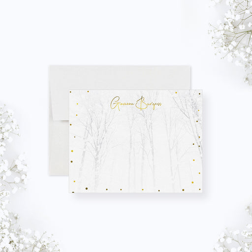 Elegant white winter note card with subtle birch tree forest illustration and scattered gold snow, personalized with a custom name in gold script.

