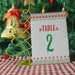 Christmas-themed table number card with decorative stand against a festive background