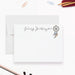 a blank, personalized note card with a name printed on it, along with a dreamcatcher illustration. The note card is placed on a white surface, surrounded by various office supplies such as a stapler, pencils, and a pair of scissors.