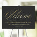 Elegant black and gold scripted welcome sign personalized with name, age, and event date, displayed on an easel for milestone birthdays or special occasions.