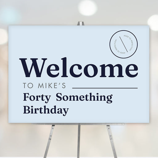 Funny forty something birthday welcome sign in light blue with navy text and aged to perfection badge, displayed on an easel for milestone party décor.
