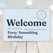 Funny forty something birthday welcome sign in light blue with navy text and aged to perfection badge, displayed on an easel for milestone party décor.