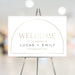 Minimalist gold arch wedding welcome sign with customizable names and date, personalized decor for ceremony or reception entrance.