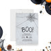 Halloween party invitation with spooky spider web design, gray textured background, spider illustration, and playful BOO lettering-front