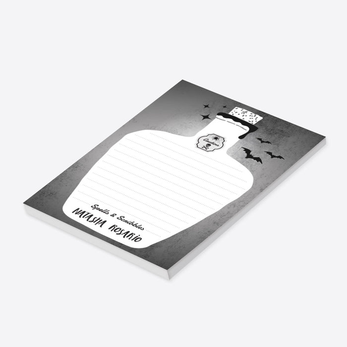 Halloween notepad with a potion bottle, decorated with bats, a spider, a skull, and a “Caution” label, personalized with your name, featuring the caption “Spells and Scribbles.”-side