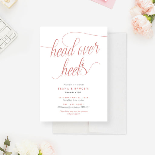 Romantic engagement invitation featuring “head over heels” in blush pink script with elegant minimalist layout-front