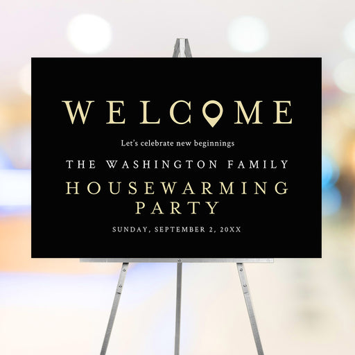 housewarming party welcome sign with black background, gold-colored lettering, location marker, and custom celebration details displayed on an easel.