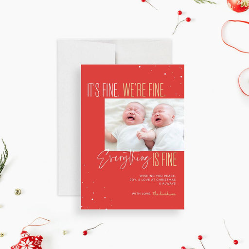 a red christmas card with a photo of two babies