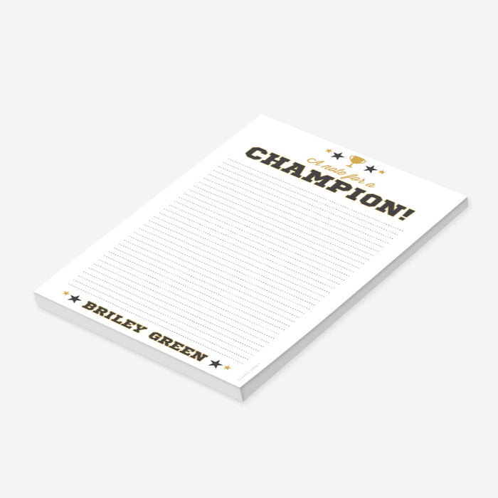 Personalized notepad featuring a trophy, varsity-style lettering, "A note for a champion!" text, and a customizable name-side