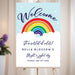 Birthday party welcome sign with a rainbow over clouds and raindrops, displayed on an easel for kids’ milestone celebrations.