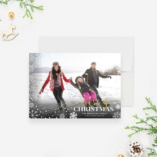 Merry Christmas photo card featuring a full-bleed family photo, white snowflake border, gold script accents and classic holiday typography on a winter-themed layout.